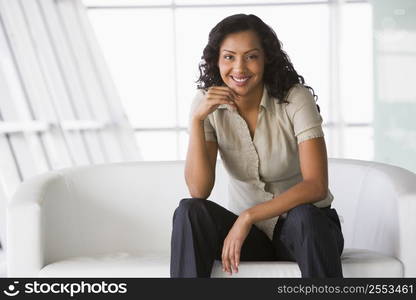 Businesswoman sitting indoors smiling (high key/selective focus)