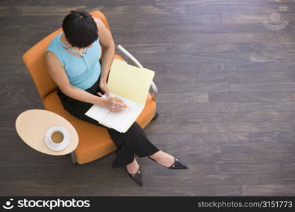 Businesswoman sitting indoors with coffee and folder