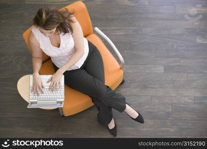 Businesswoman sitting indoors with laptop