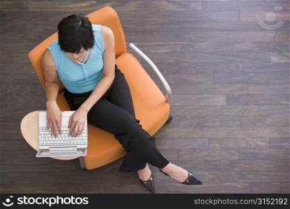 Businesswoman sitting indoors with laptop
