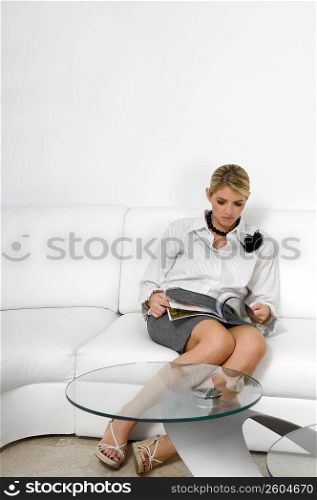 Businesswoman sitting on a couch and reading a magazine