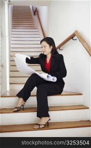 Businesswoman sitting on a staircase and looking at charts