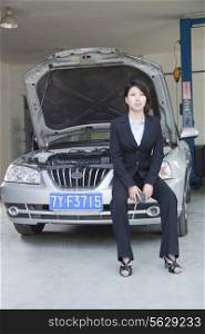 Businesswoman Sitting on Car With Open Hood