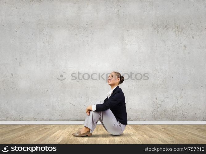 Businesswoman sitting on floor. Young attractive lady sitting on floor of empty room