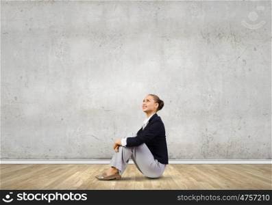 Businesswoman sitting on floor. Young attractive lady sitting on floor of empty room