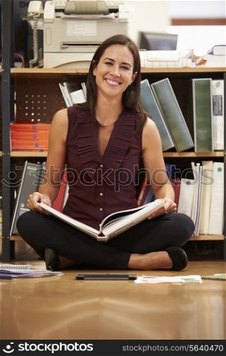 Businesswoman Sitting On Office Floor Reading Documents
