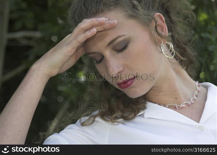 Businesswoman sitting outdoors resting her head in her hand, trying to suppress an upcoming headache