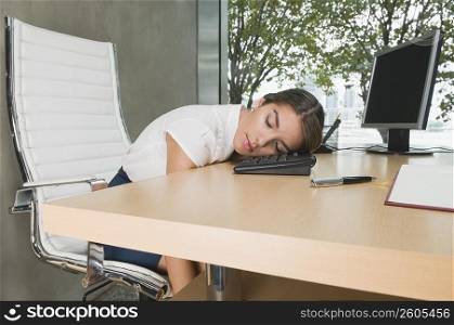 Businesswoman sleeping on a desk in an office