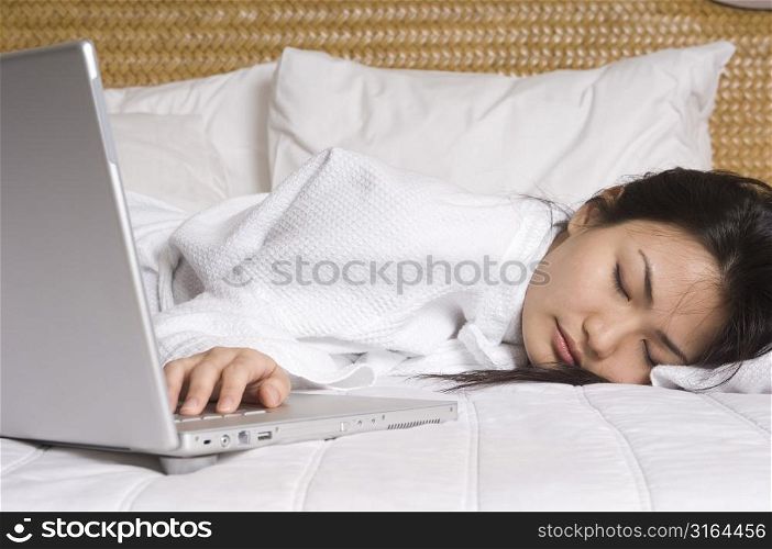 Businesswoman sleeping on the bed beside a laptop
