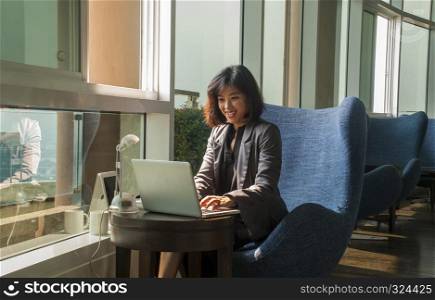 Businesswoman smiling while working with a laptop And a lamp placed beside her in the office