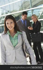 Businesswoman smiling with colleagues in background, outdoors