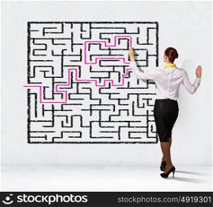 Businesswoman solving maze problem. Back view image of young businesswoman trying to find way in labyrinth