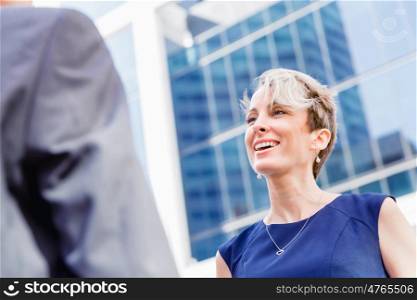 Businesswoman standing and talking to her colleague outdoors. Nice talk out of the office