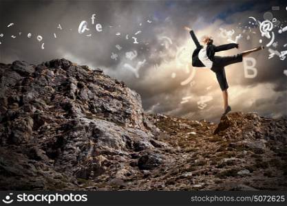 businesswoman standing atop of mountain. young businesswoman standing on one leg atop of mountain against diagram background