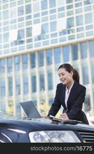 Businesswoman Standing by Car Using Laptop and Writing