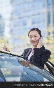 Businesswoman Standing by Car Using Phone, Looking At Camera
