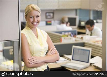 Businesswoman standing in cubicle smiling