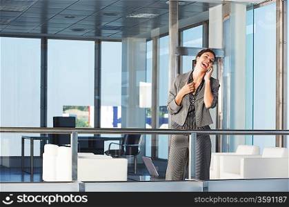 Businesswoman standing in office talking on mobile phone
