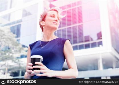 Businesswoman standing next to her office and holding a coffee. Businesswoman with coffee in a city