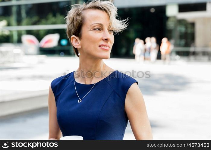 Businesswoman standing next to her office and holding a coffee. Businesswoman with coffee in a city