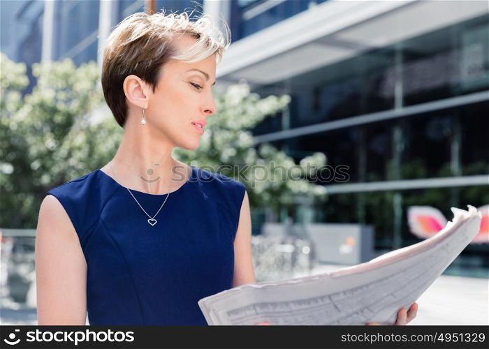 Businesswoman standing next to her office with newspaper. New business day is ahead