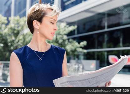Businesswoman standing next to her office with newspaper. New business day is ahead