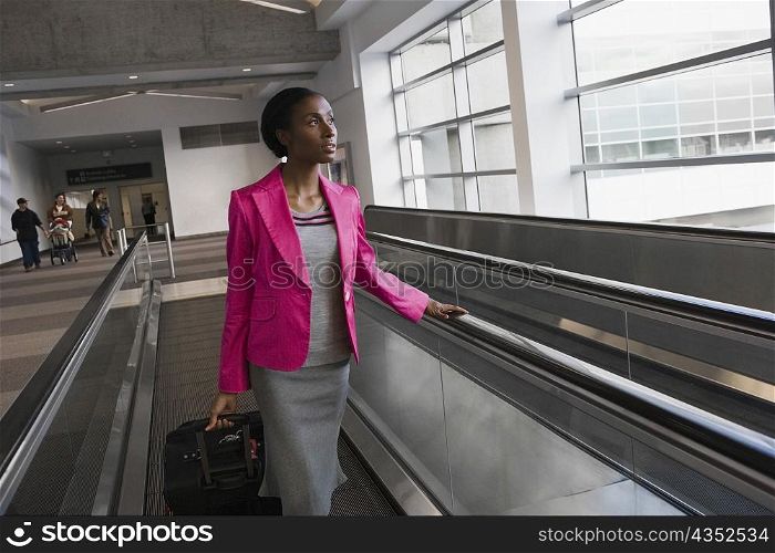 Businesswoman standing on an escalator at an airport
