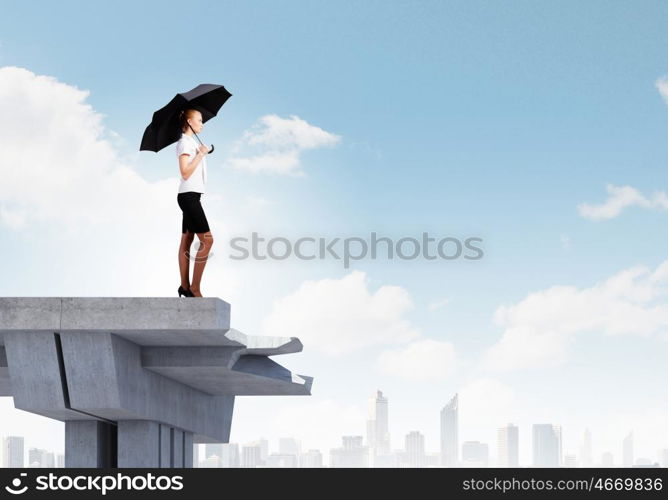 Businesswoman standing on bridge. Young businesswoman with umbrella standing on bridge