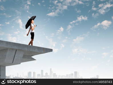 Businesswoman standing on bridge. Young businesswoman with umbrella standing on bridge