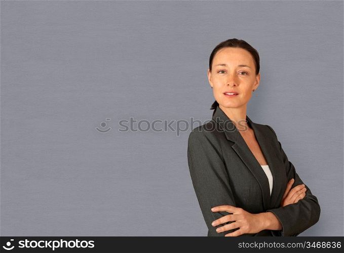 Businesswoman standing on grey background with arms crossed