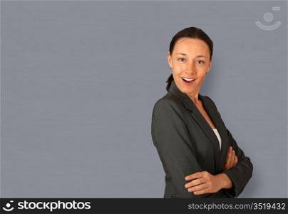 Businesswoman standing on grey background with arms crossed