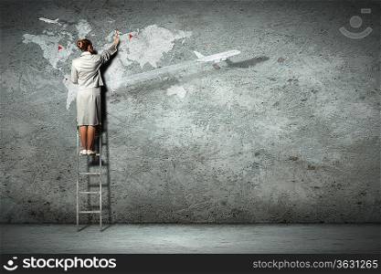 Businesswoman standing on ladder and pointing on map picture on wall