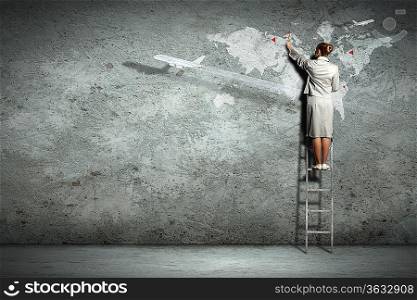Businesswoman standing on ladder and pointing on map picture on wall