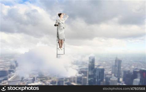 Businesswoman standing on ladder. Businesswoman standing on ladder looking into distance against city background