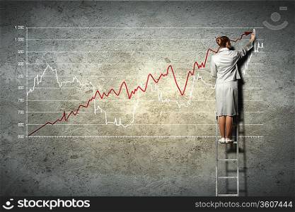businesswoman standing on ladder drawing diagrams and graphs on wall