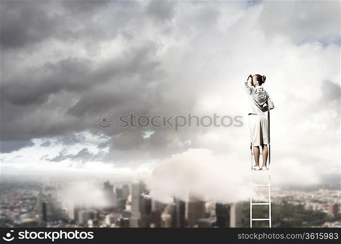 Businesswoman standing on ladder looking into distance against city background