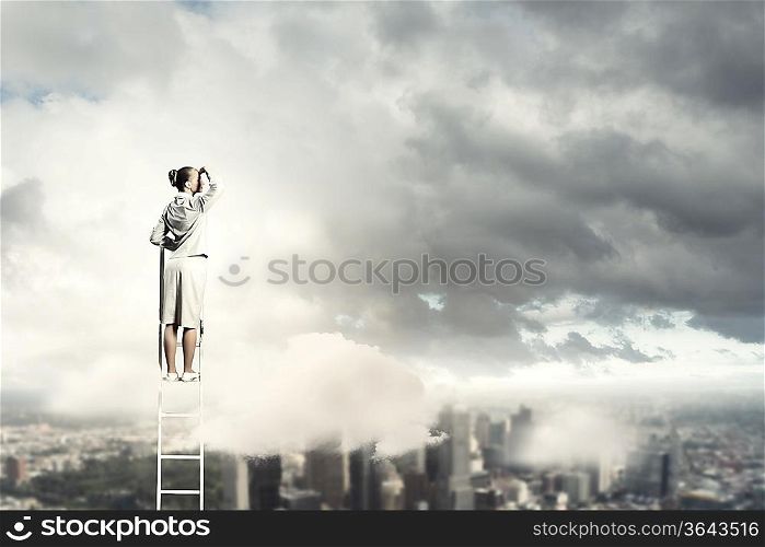 Businesswoman standing on ladder looking into distance against city background