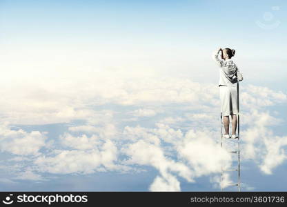 Businesswoman standing on ladder looking into distance against cloudy background