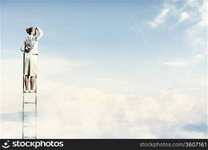 Businesswoman standing on ladder looking into distance against cloudy background