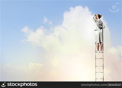 Businesswoman standing on ladder looking into distance against cloudy background