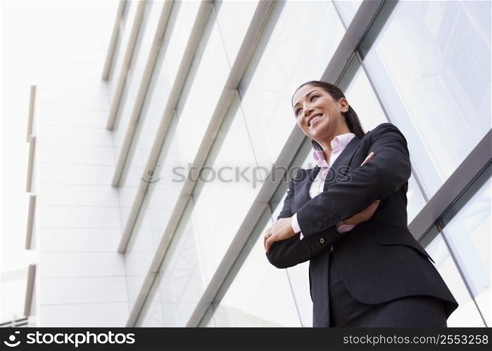 Businesswoman standing outdoors by building smiling (high key/selective focus)