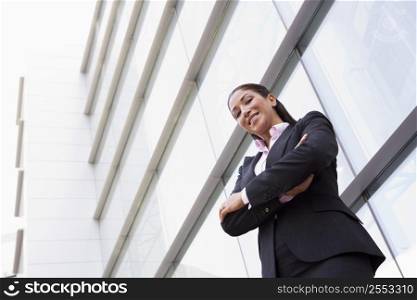Businesswoman standing outdoors by building smiling (high key/selective focus)