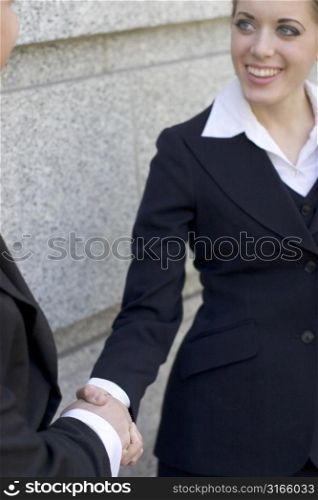 Businesswoman standing outside and giving a handshake