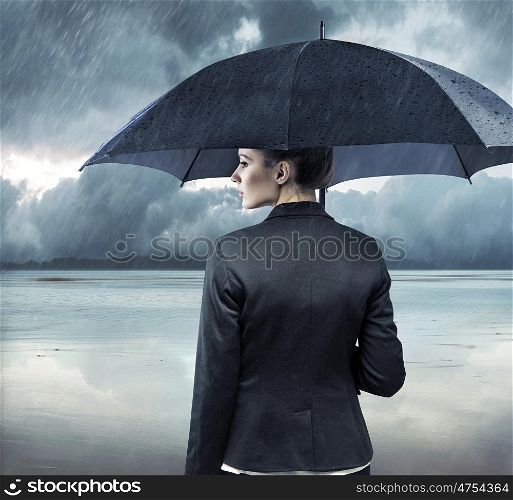 Businesswoman standing with an black umbrella