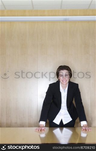 BusinessWoman standing with her hands on the table and a smile on her face in the board room