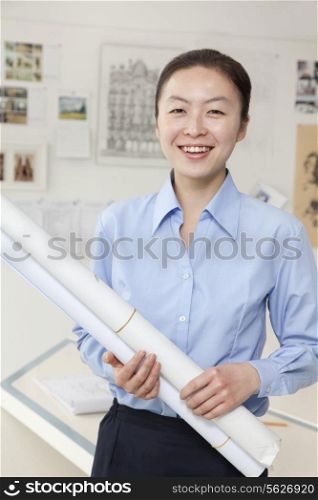 Businesswoman standing with stuck of papers in the office, portrait
