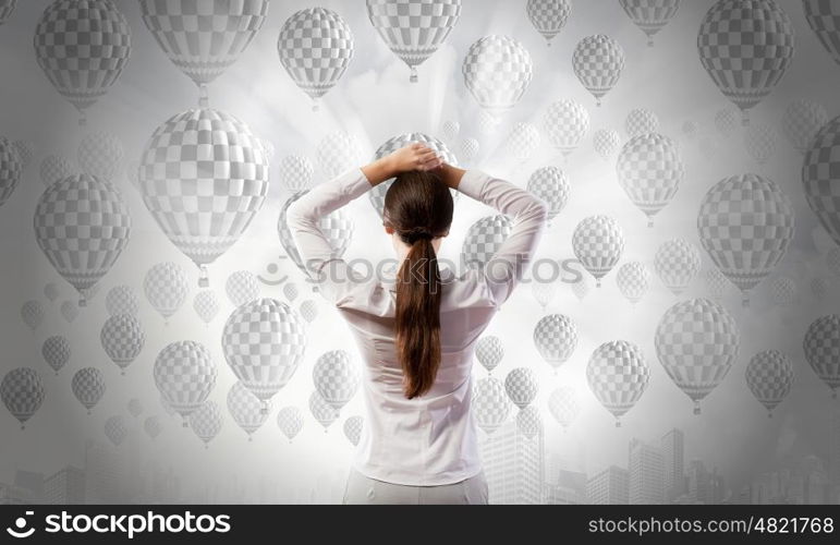 Businesswoman stands back and looks at flying objects. Making decision