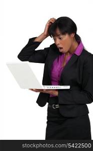 Businesswoman staring in shock at her laptop