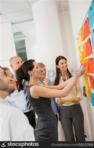 Businesswoman sticking labels on whiteboard during meeting