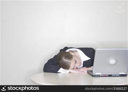 Businesswoman taking a nap next to her laptop while working